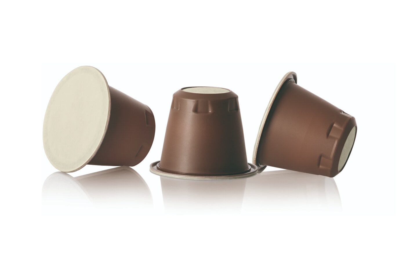 Drei braune NAT®Cap Home Kaffeekapseln von säntis packaging mit kompostierbarem Deckel – nachhaltige, biobasierte Alternative zu herkömmlichen Aluminiumkapseln.