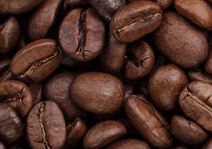 Makroaufnahme gerösteter Kaffeebohnen – Symbolbild für Kaffeeprodukte und nachhaltige Kapsellösungen von säntis packaging.