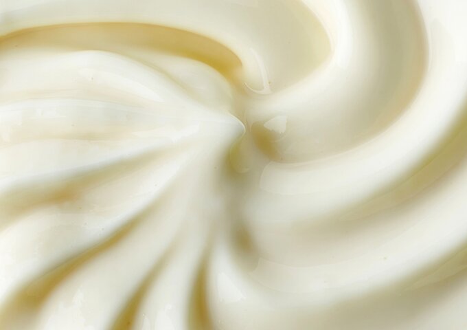 Cremige, weisse Joghurt- oder Dessertmasse in Nahaufnahme – glatt gerührt und frisch, als Symbol für Molkerei- und Kühlprodukte.
