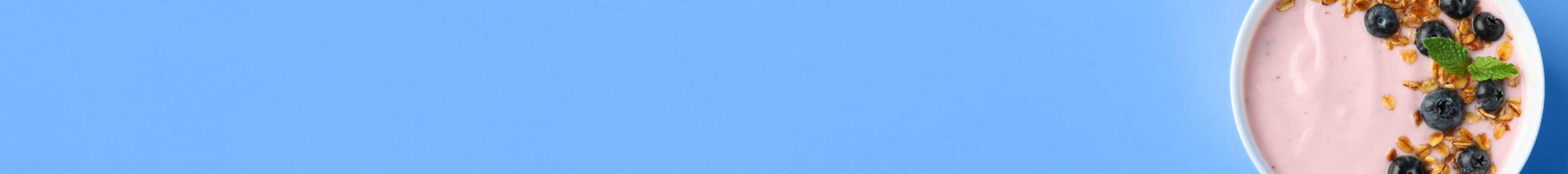 Schale mit Joghurt, Blaubeeren und Granola auf hellblauem Hintergrund – Symbolbild für frische Lebensmittel und nachhaltige Verpackungslösungen von säntis packaging.