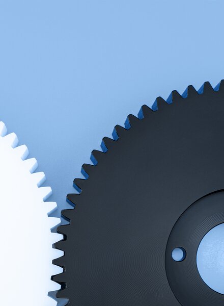 Weisse und schwarze Kunststoffzahnräder auf hellblauem Hintergrund – präzise gefertigte, funktionale und recyclingfähige Komponenten von säntis packaging für technische Anwendungen.