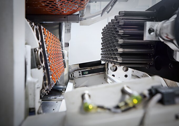 Tiefziehform mit orangefarbenen Kunststoffbechern – präzise und effiziente Thermoform-Technologie von säntis packaging.