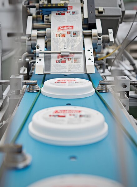 Automatisierte Etikettieranlage von säntis packaging – präzises Aufbringen von Etiketten auf Kunststoffdeckel in gleichbleibender Qualität.