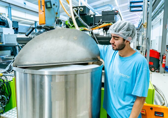 Lernender bei säntis packaging kontrolliert Kunststoffgranulat in einem grossen Edelstahltank – Überprüfung des Rohmaterials für die Kunststoffproduktion.