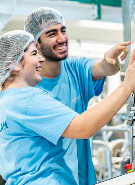 Zwei Lernende bei säntis packaging bedienen gemeinsam ein digitales Steuerungspanel einer Produktionsmaschine – Ausbildung in moderner Kunststoffverarbeitung mit Fokus auf Technik und Teamarbeit.