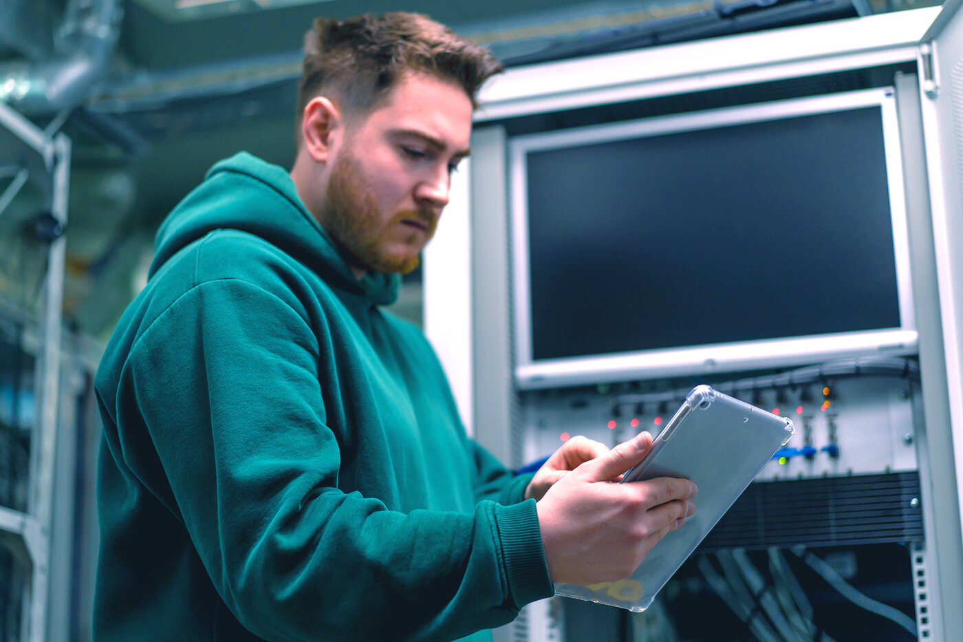 Student im technischen Umfeld arbeitet mit Tablet an einem Serversystem – praxisnahes Lernen und Digitalisierung bei säntis packaging im Rahmen eines Studiums oder Praktikums.