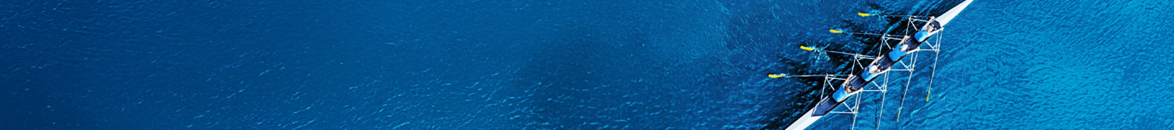 Luftaufnahme eines Ruderteams auf tiefblauem Wasser – Symbol für Teamwork, gemeinsame Richtung und den Start in die berufliche Zukunft bei säntis packaging.