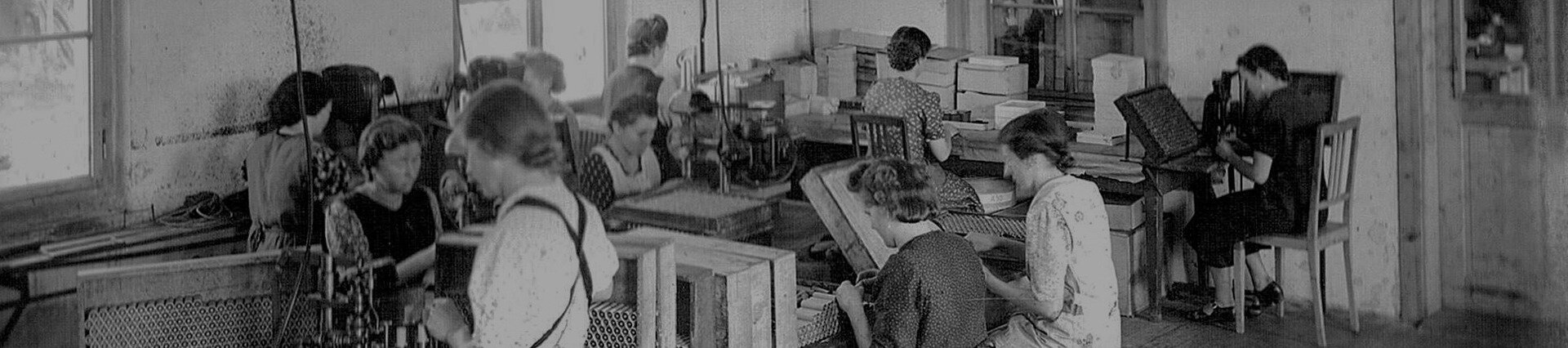 Historische Aufnahme aus den Anfangsjahren von säntis packaging: Arbeiterinnen fertigen in einer Werkstatt Batterieteile – Sinnbild für den Ursprung des Unternehmens im Jahr 1922 und den Beginn einer über hundertjährigen Industriegeschichte.