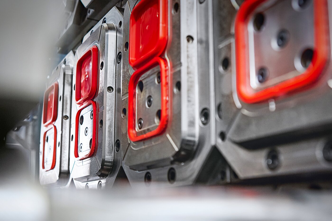 Detailaufnahme eines IML-Spritzgusswerkzeugs mit roten Formelementen – Symbol für den Technologievorsprung von SÄNTIS seit 2016 im Bereich dekorativer In-Mould-Labeling-Verpackungen.