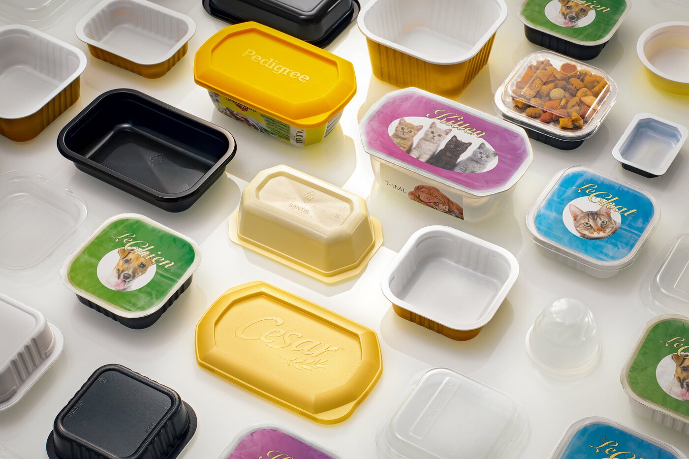 Verschiedene PET-Schalen und Dosen für Tiernahrung in unterschiedlichen Formen und Farben – Symbol für die 2008 von SÄNTIS entwickelten transparenten, wiederverschliessbaren Premiumverpackungen für Pet-Food.