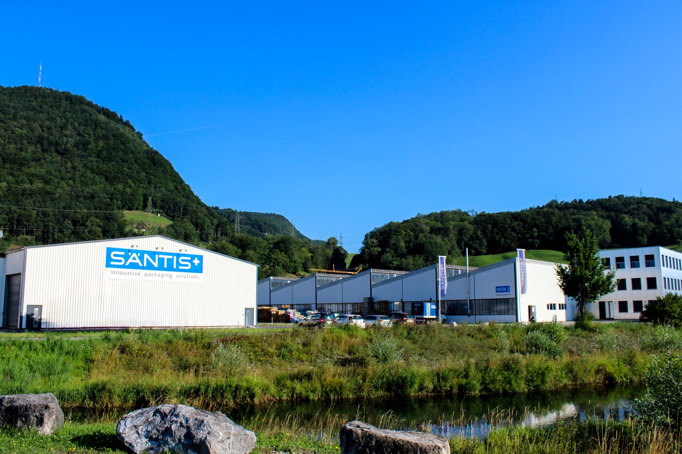 Aussenansicht des Firmengebäudes der säntis packaging ag inmitten grüner Hügel – Symbolbild für die strategische Eigenständigkeit ab 2010 und den Beginn der unabhängigen Entwicklung des Verpackungsunternehmens.