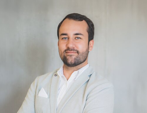 Porträt von Benjamin Fleisch, Head of Marketing & Digital Business bei säntis packaging ag – in hellem Sakko und weissem Hemd, freundlich und selbstbewusst vor neutralem Hintergrund fotografiert.