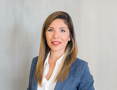 Porträt von Suzan Altuntas, Key Account Manager bei säntis packaging ag – in weissem Hemd und blauem Blazer, freundlich lächelnd vor hellem Hintergrund fotografiert.