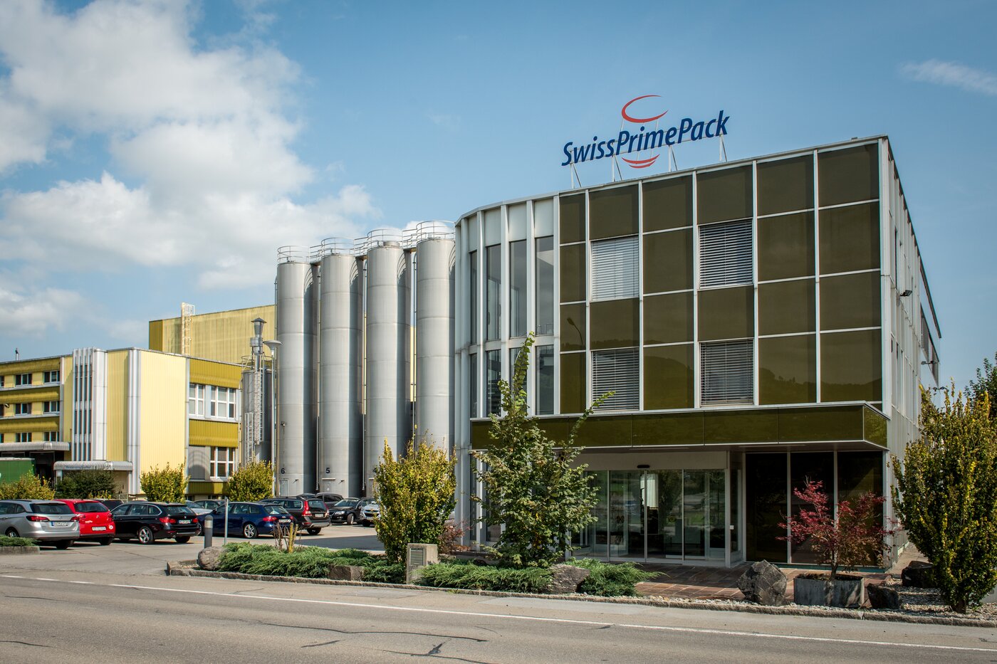 Firmengebäude von SwissPrimePack mit Produktionsanlage und Silos in der Schweiz – Standort und Teil der Säntis Packaging Gruppe für hochwertige Verpackungslösungen.