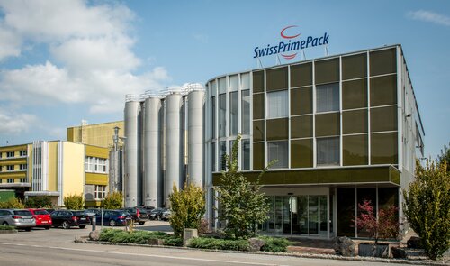Firmengebäude von SwissPrimePack mit Produktionsanlage und Silos in der Schweiz – Standort und Teil der Säntis Packaging Gruppe für hochwertige Verpackungslösungen.