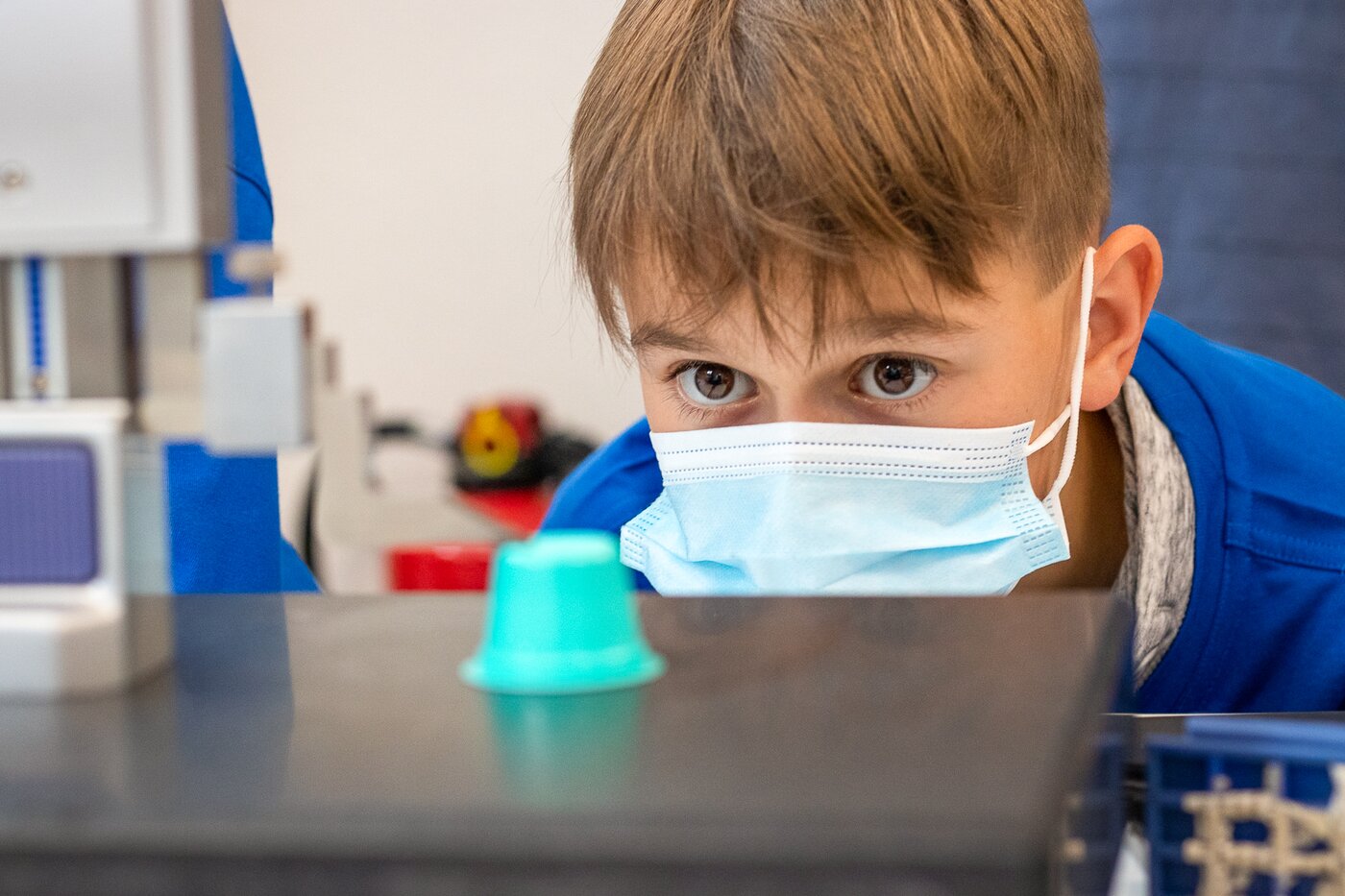 Junge Teilnehmer beobachtet aufmerksam eine grüne Kunststoffkapsel während der Qualitätsprüfung bei den Young-Tec-Days von Säntis Packaging.