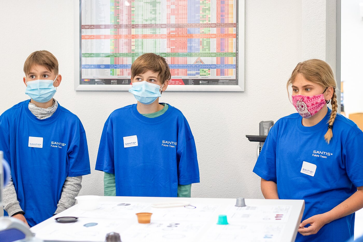 Drei Kinder in blauen Säntis Packaging T-Shirts bei den Young-Tec-Days in Rüthi – Nachwuchsförderung mit Einblicken in CAD, 3D-Druck und Kunststoffverarbeitung.