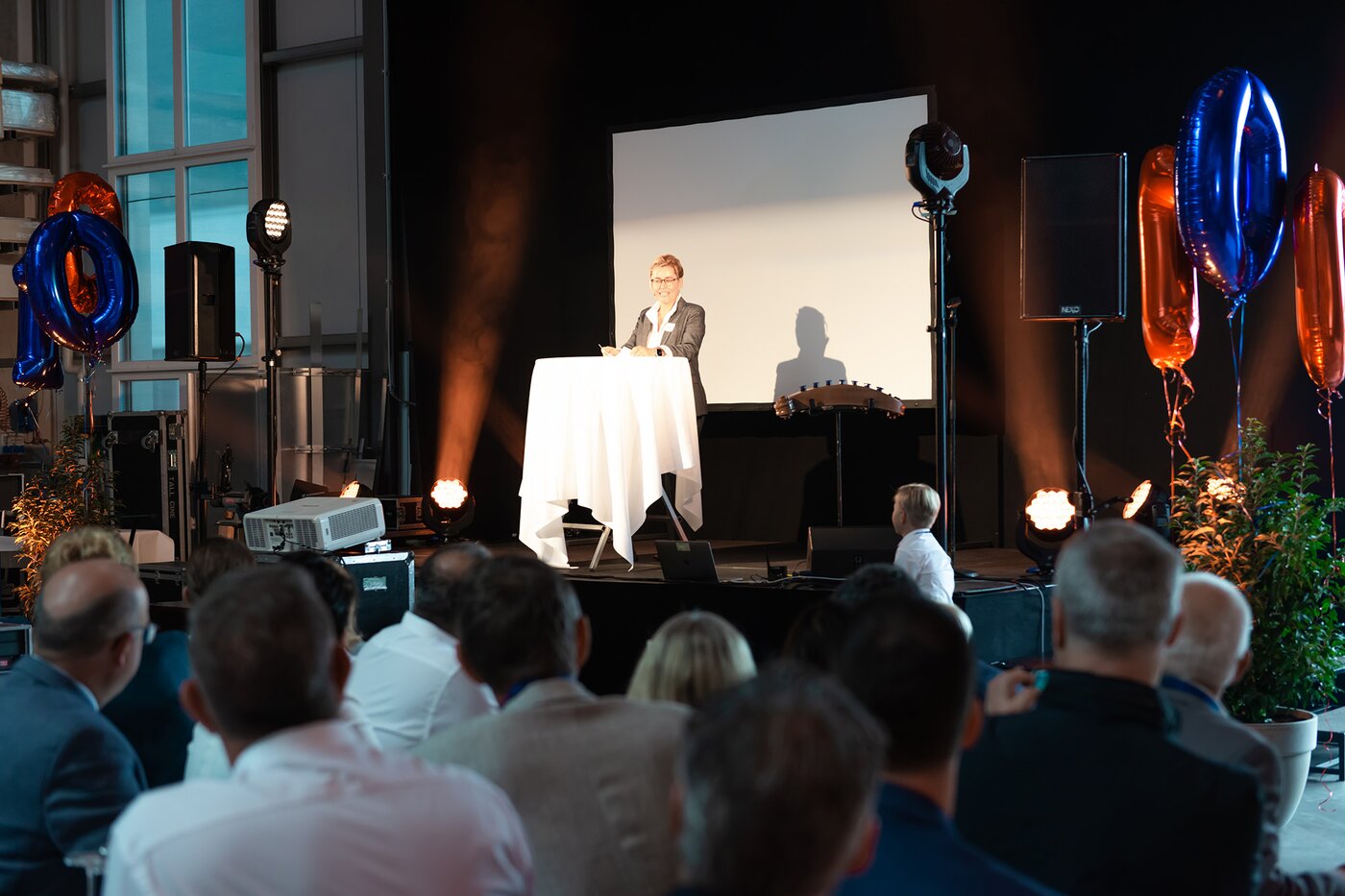 Inhaberin Dr. Bettina Fleisch hält ihre Festrede auf der Bühne während der 100-Jahr-Feier der SÄNTIS-Gruppe in Rüthi – Jubiläumsveranstaltung mit Publikum und festlicher Beleuchtung.